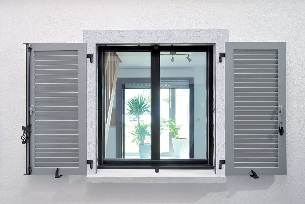 Volets battants aluminium gris encadrant une fenêtre